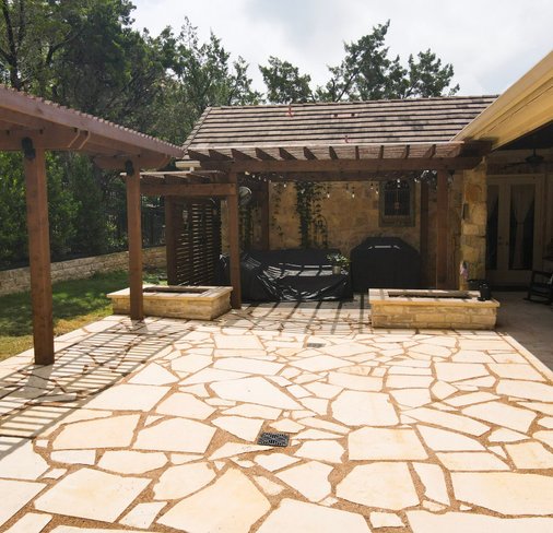 Flagstone patio with stone planters and a pergola at a Lakeway home