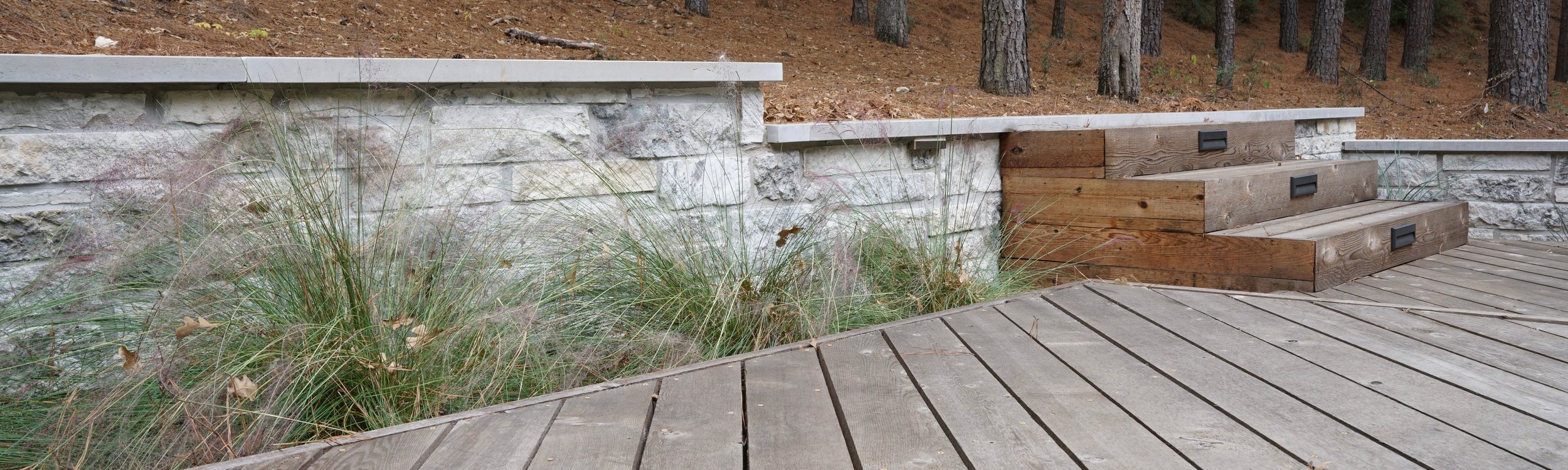 Multi-level deck with steps and a retaining wall on a sloped Lost-Pines lot