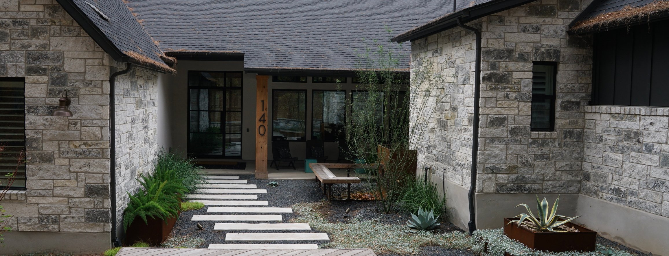 Bastrop Lost Pines courtyard with paver patio, corten-steel planters, and xeriscape plantings by Thrive Landscape and Design