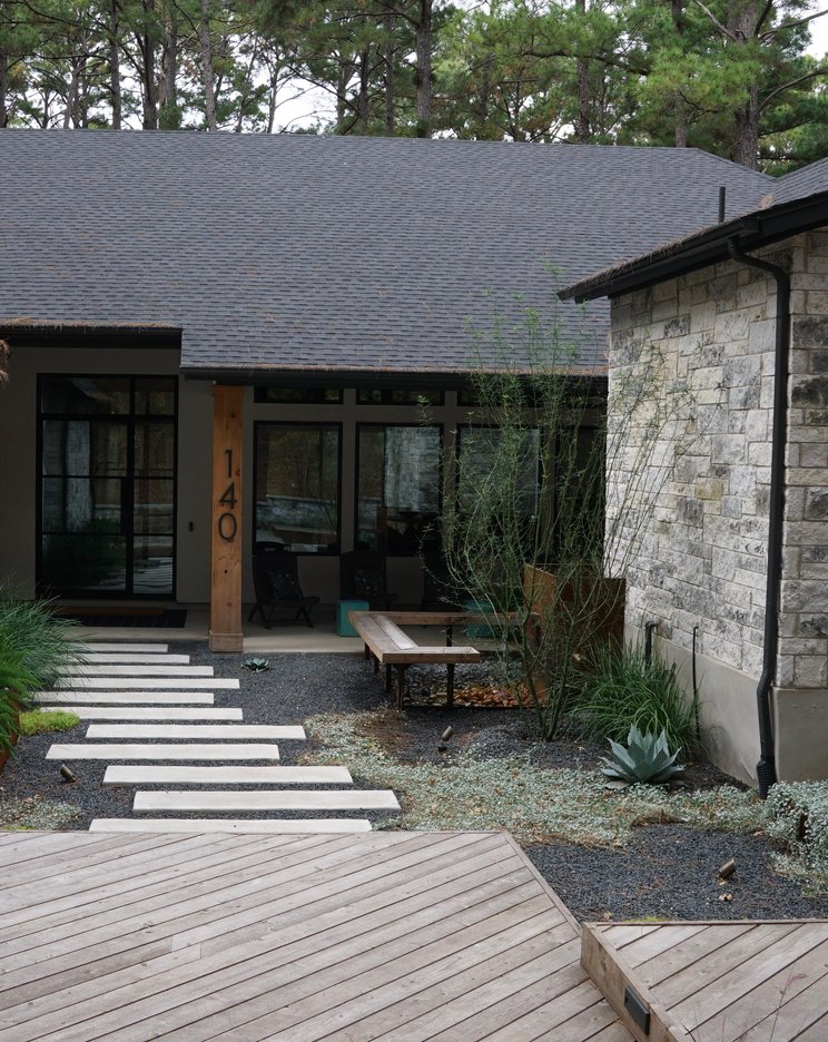 Paver patio with a deck, planters, and xeriscape plantings on a Lost-Pines property