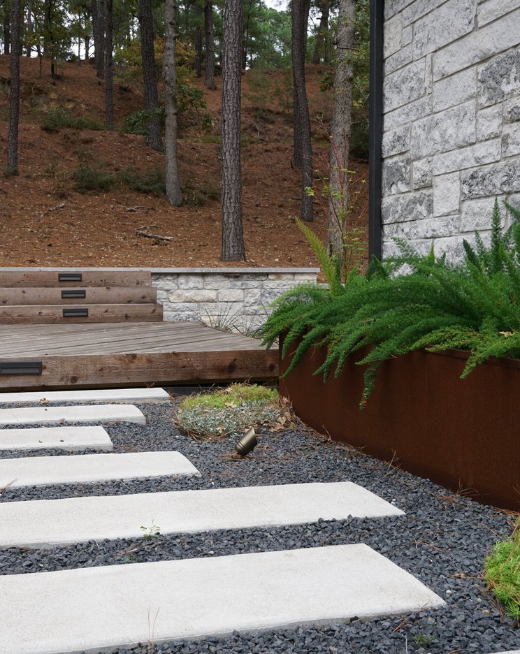 Lost-Pines xeriscape with pavers, gravel, and planters by a deck