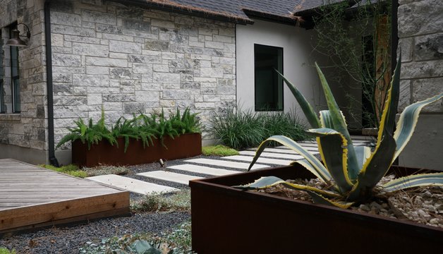 Interlocking paver patio with planters beside a deck at a Bastrop-area home