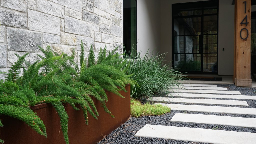 Finished paver patio with set joints, planters, and gravel landscaping on a Lost-Pines property