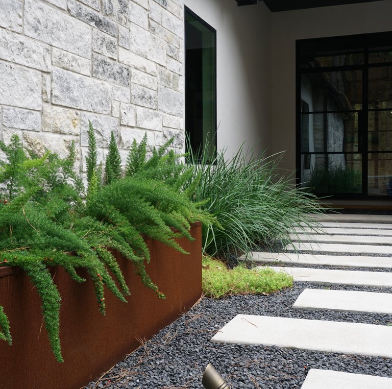 Bastrop Lost Pines landscaping with pavers, planters, and gravel beds among the pines
