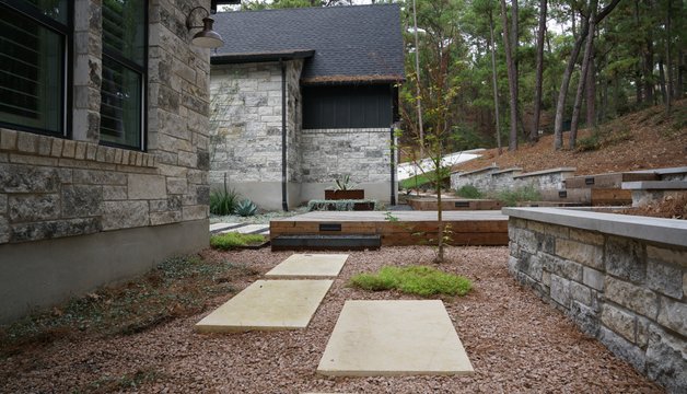 Lost-Pines xeriscape with pavers and a stone retaining wall