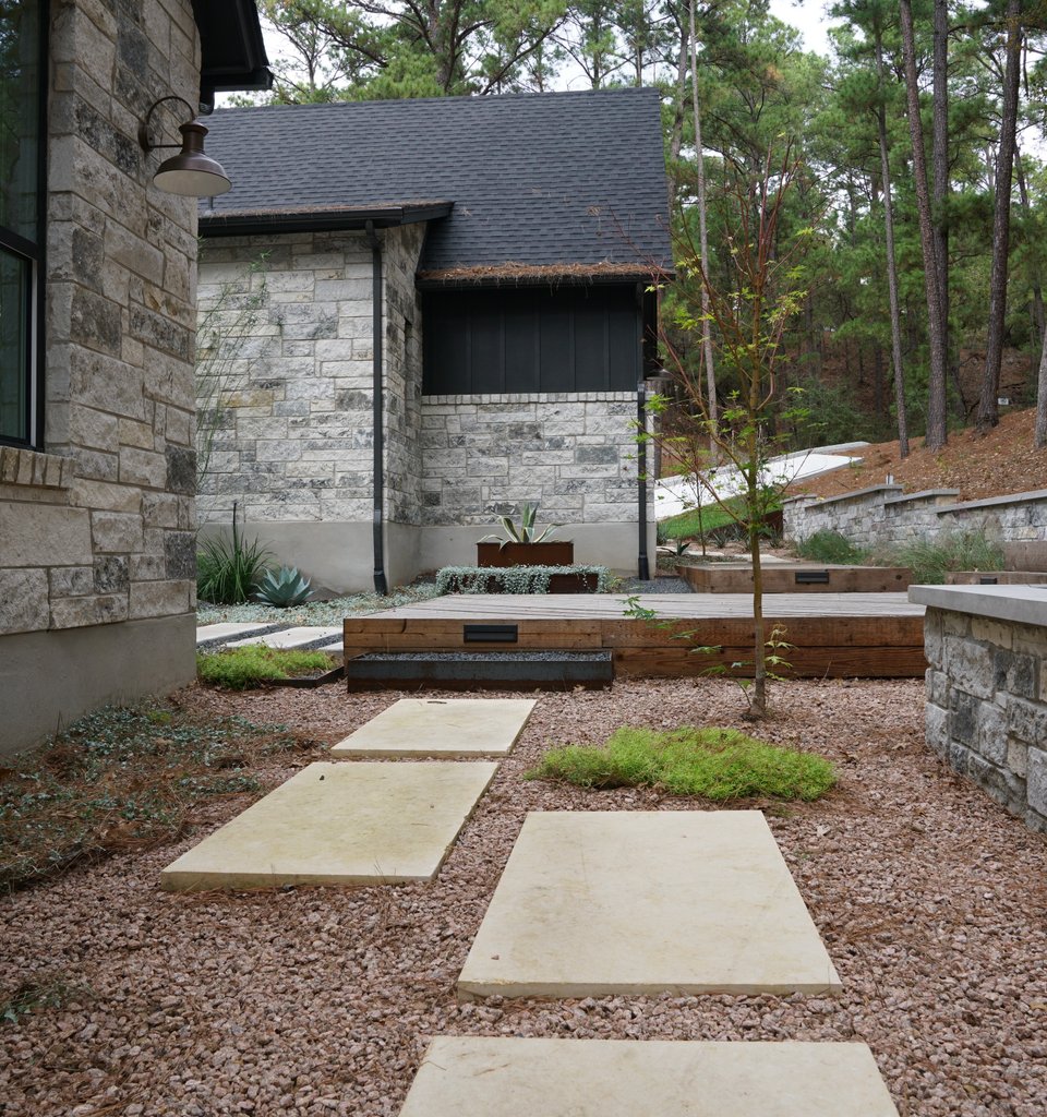 Bastrop Lost-Pines property with a retaining wall and xeriscape planting holding the grade