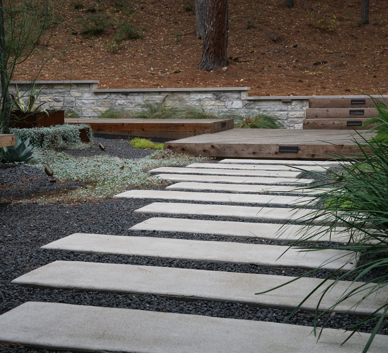 Bastrop Lost-Pines courtyard with paver walkway, limestone walls, and a deck