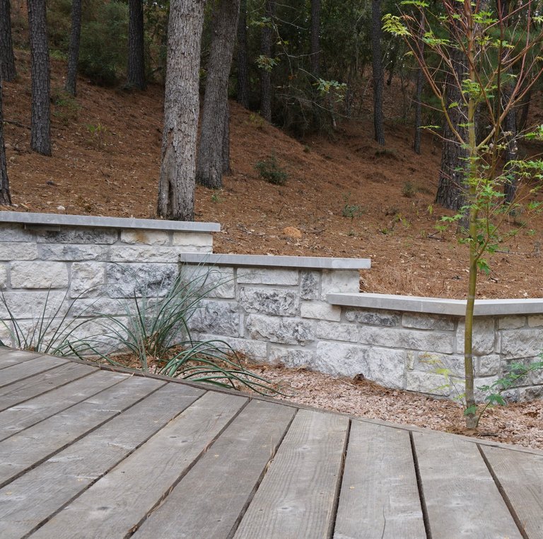 Stone retaining wall and deck in a Bastrop Lost Pines backyard