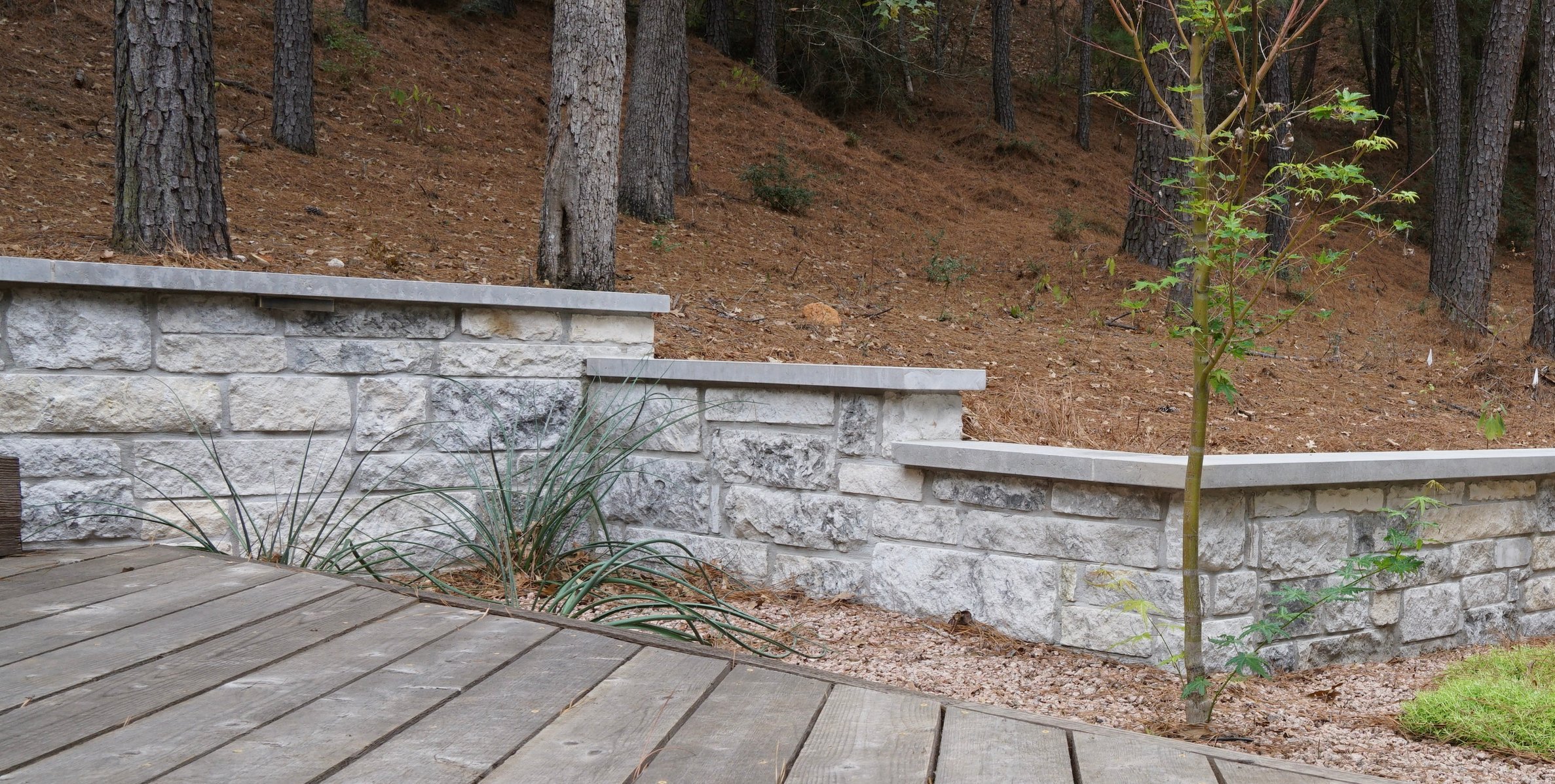 Chunky limestone retaining walls holding the hillside beside the deck