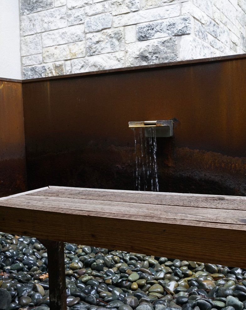 Lost Pines courtyard water feature with bench seating and river-rock border in Bastrop