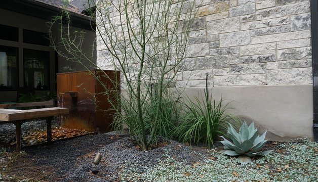Gravel drainage bed channeling water through a Bastrop-area landscape