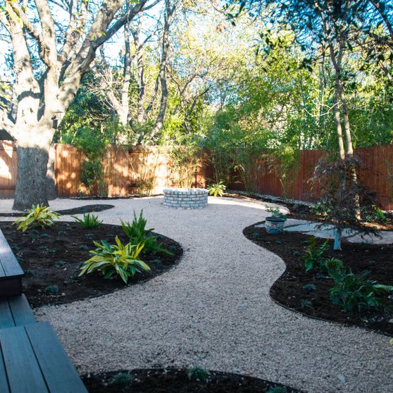 Elevated deck with a firepit and planting beds in a shaded Riverplace garden