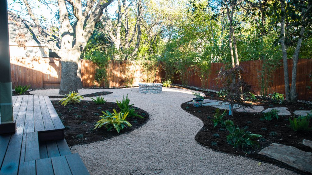 Deck under construction beside a firepit and planting beds on a shaded Riverplace lot