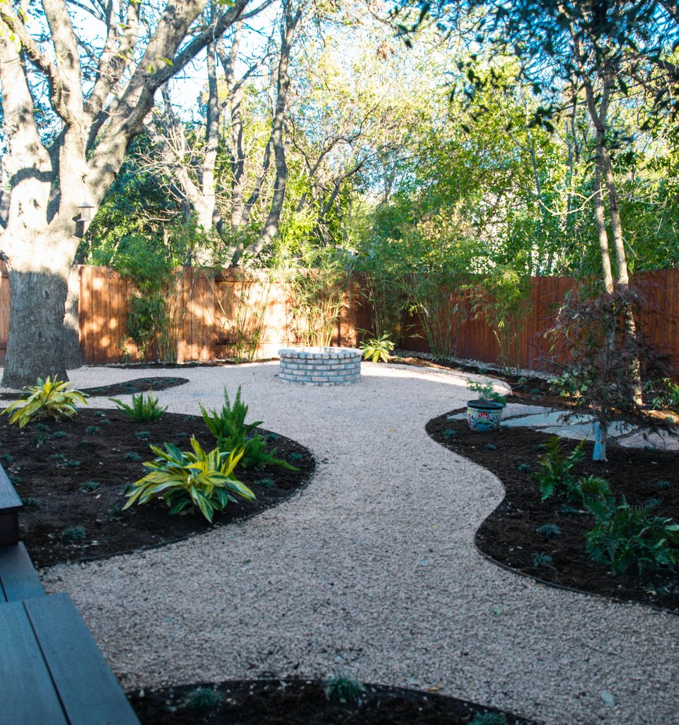 River Place shaded garden with mulched planting beds around a deck and fire pit