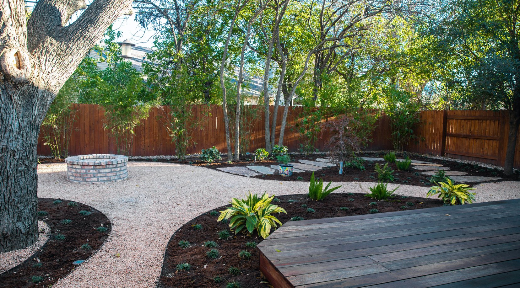Hostas, ferns, and grasses filling the curved decomposed granite beds
