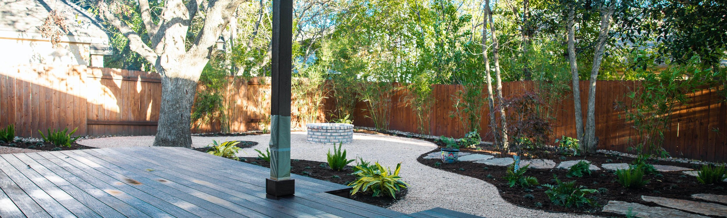 Riverplace shaded garden with a deck, fire pit, and decomposed granite planting beds