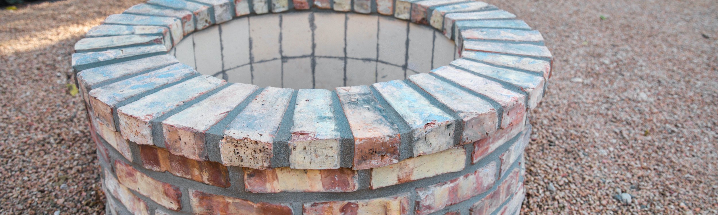 Close-up of a built-in brick fire pit set in a decomposed granite garden near Austin