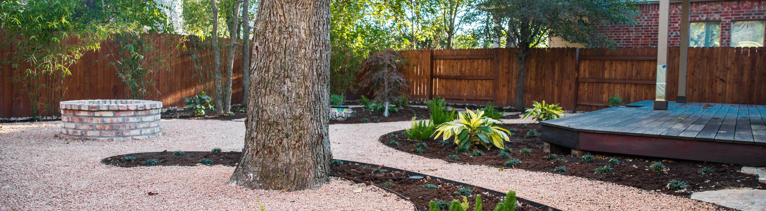 A Riverplace, Austin TX shaded garden with a deck, fire pit, and decomposed granite planting beds by Thrive Landscape and Design
