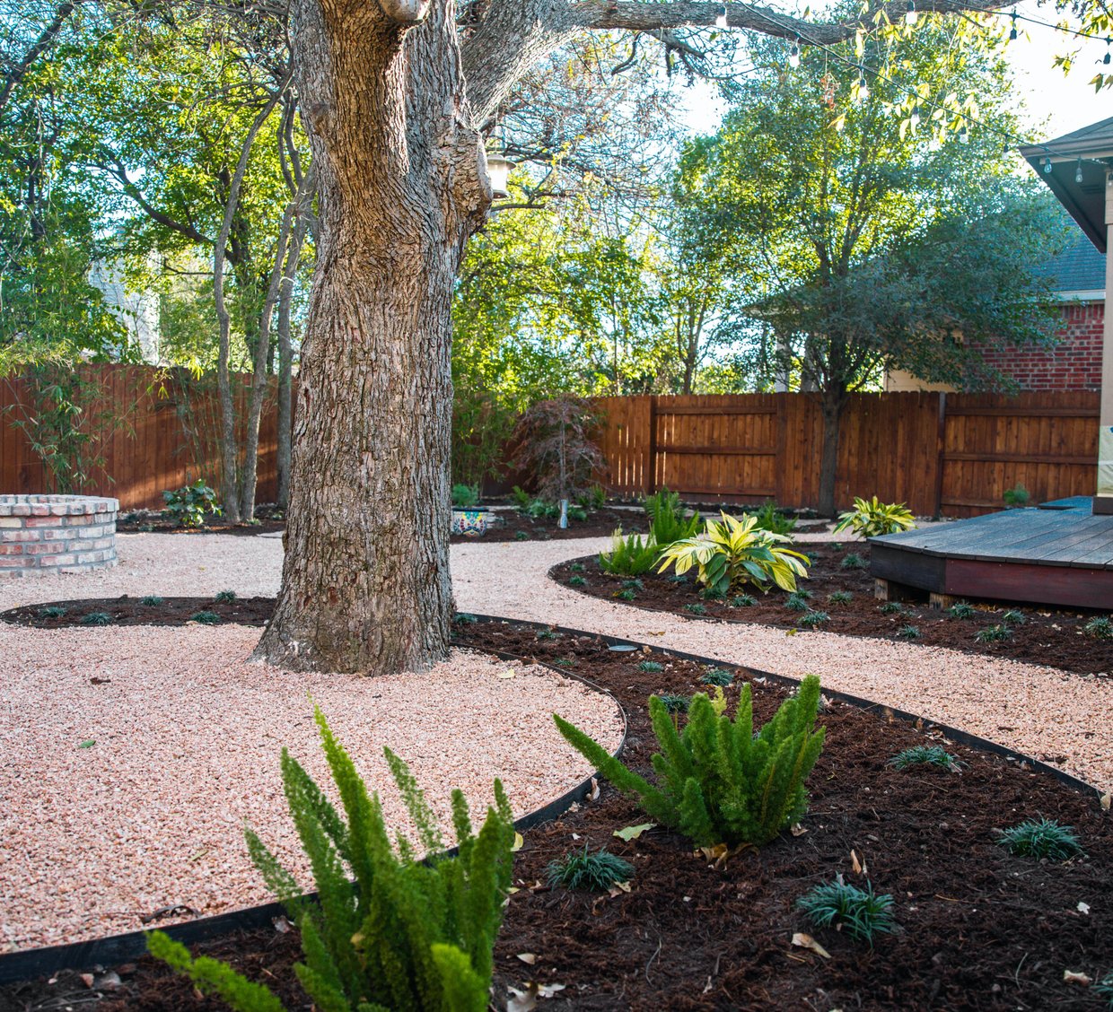 Riverplace shaded garden with a deck, fire pit, and decomposed granite beds