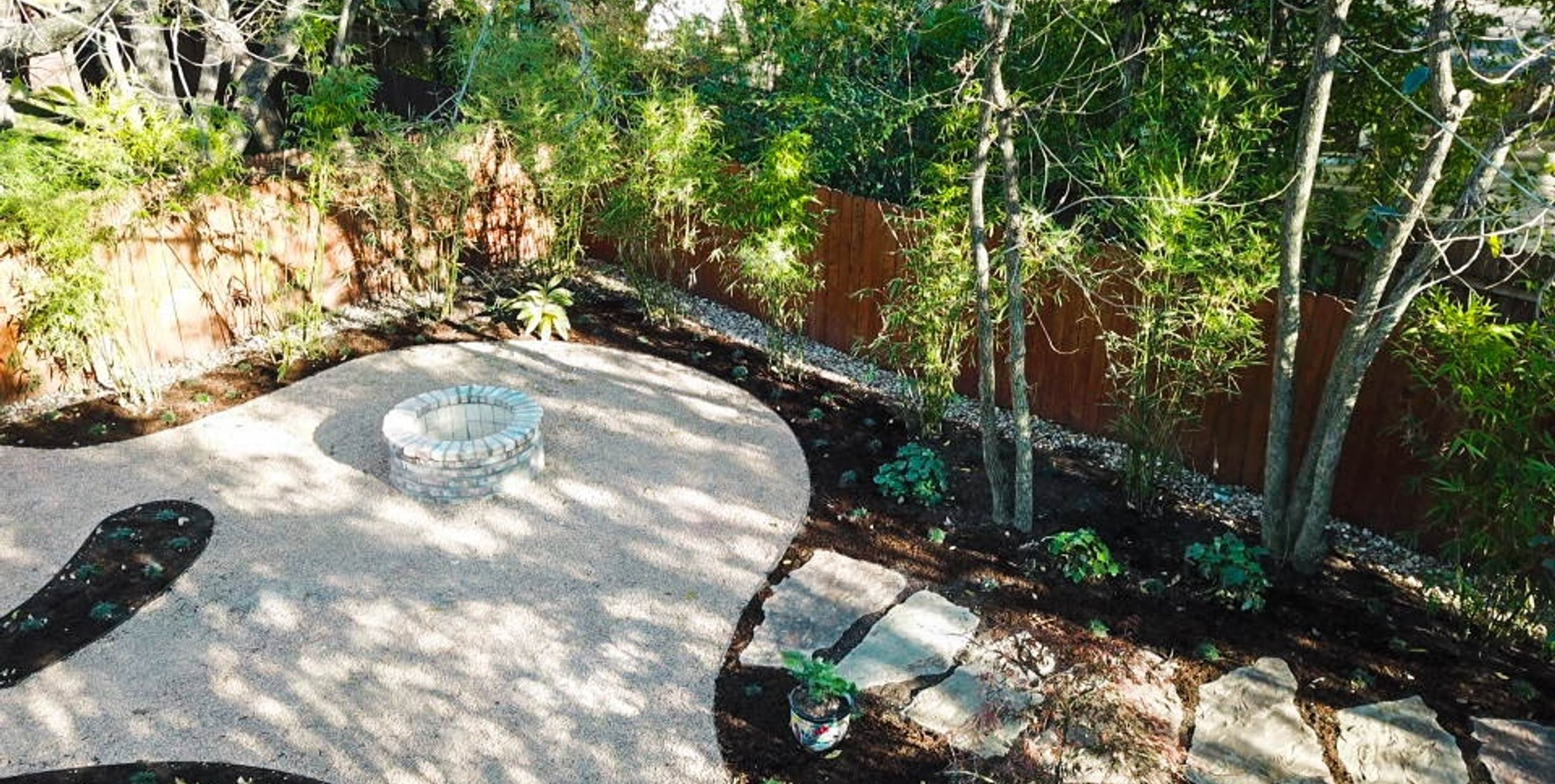 Brick fire pit and flagstone framed by decomposed granite and bamboo privacy screen