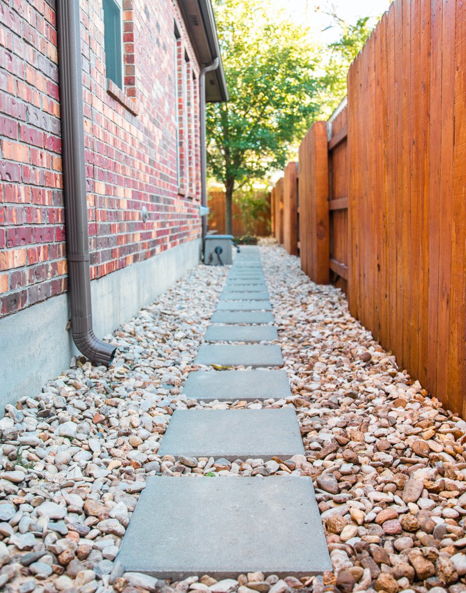 Square concrete pavers set into river rock along the side-yard utility path
