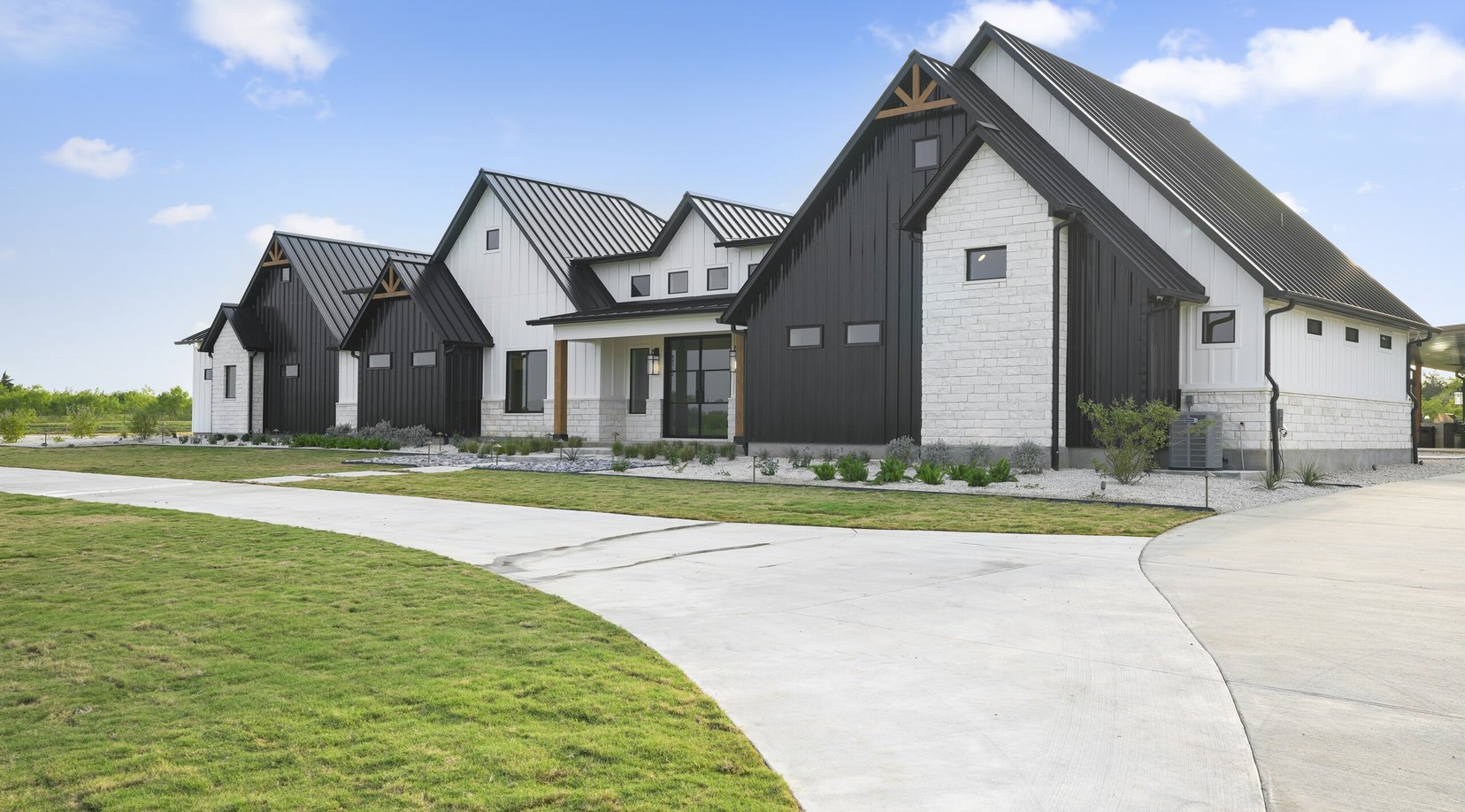 Curved concrete driveway beside gravel planting beds held by custom welded steel edging
