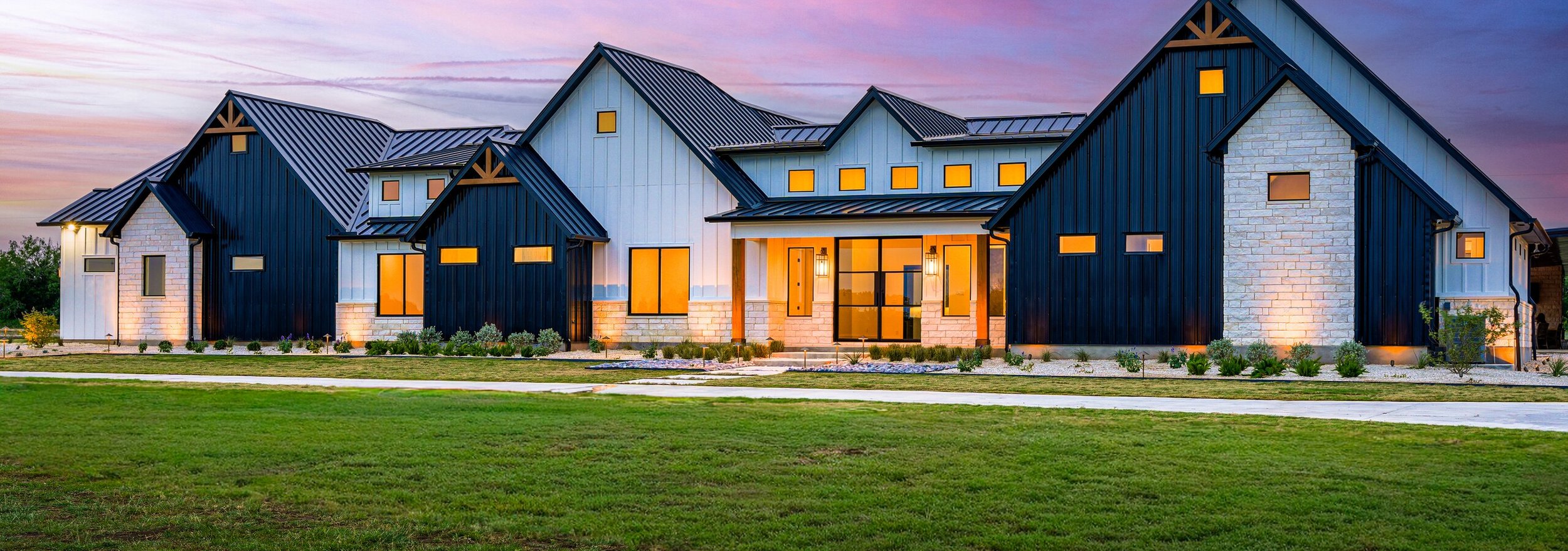 The completed landscape at sunset with every bed, column, and gable picked out by low voltage lighting