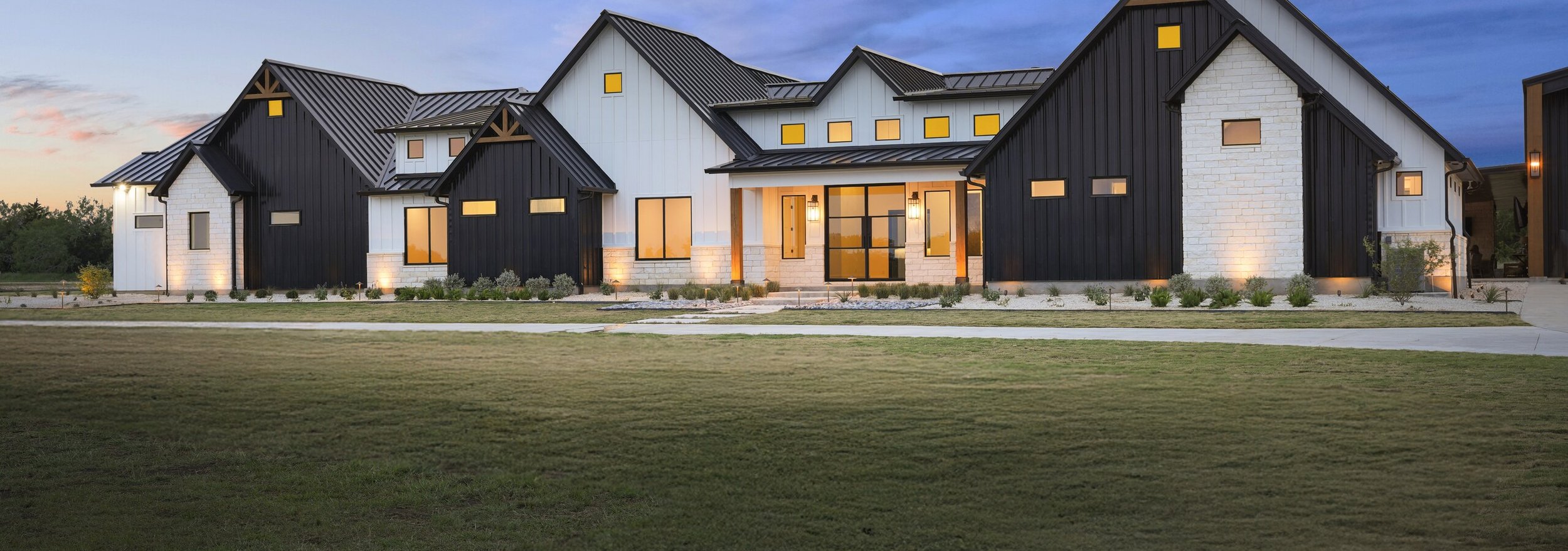 Full front elevation at dusk with the new zoysia lawn running out to the drive