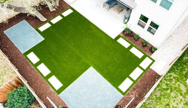 Aerial view of a Round Rock backyard with healthy turf, stepping stones, a patio, and planting beds