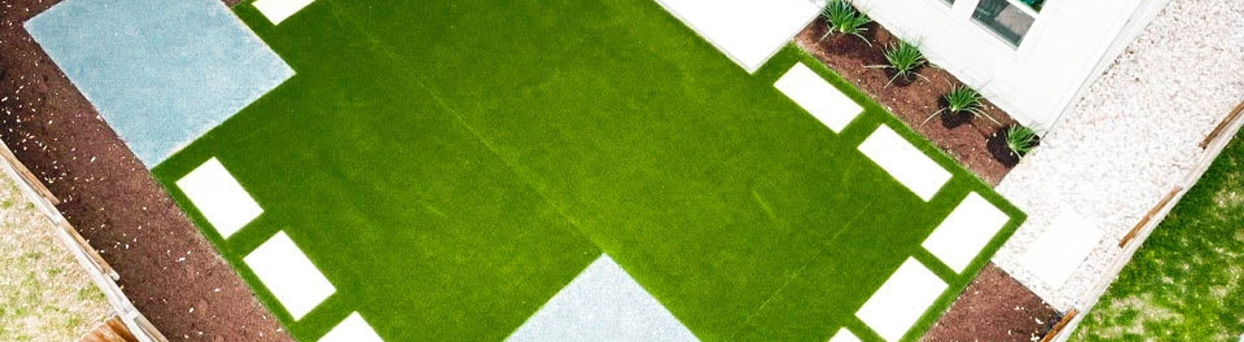 Aerial view of a Round Rock, TX backyard with cream pavers laid into synthetic turf in a checkerboard pattern by Thrive Landscape and Design