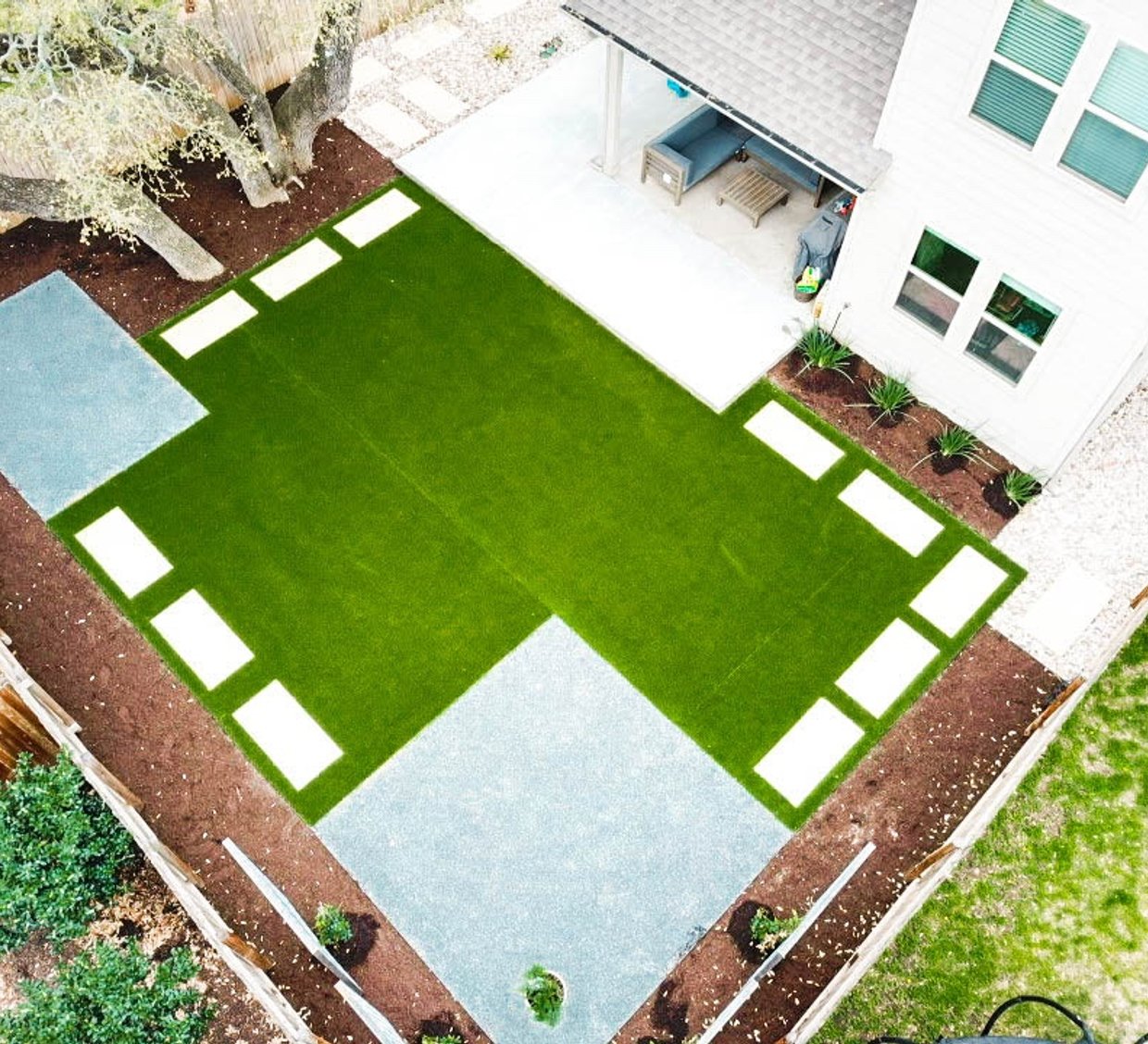 Round Rock backyard with cream pavers set into synthetic turf in a checkerboard pattern