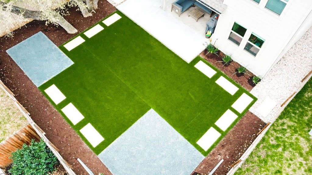 Cream pavers set into synthetic turf in a checkerboard pattern at a Round Rock backyard