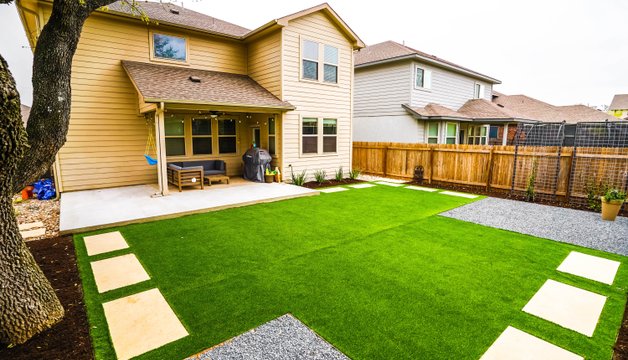 Synthetic turf with stepping stones and gravel in a Round Rock backyard