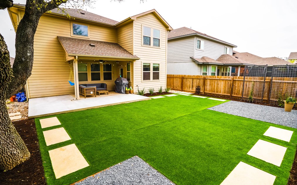 Round Rock backyard with turf panels, stepping stones, gravel, and planting beds watered on separate irrigation zones