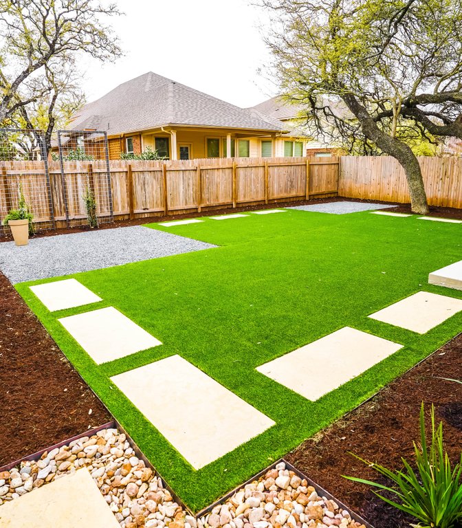 Even green turf and mixed planting zones in a Round Rock backyard kept healthy on one watering day a week