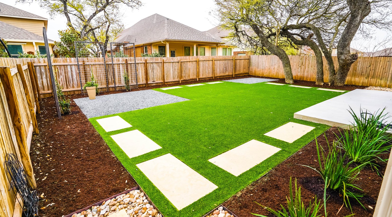Checkerboard turf and pavers with river rock and perimeter mulch beds
