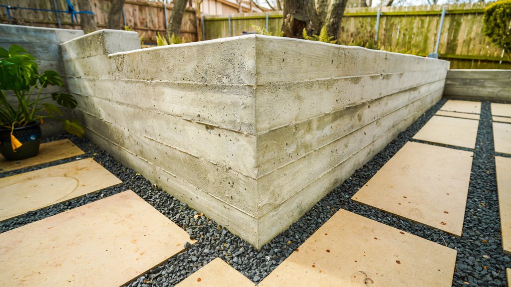 Graded base with a gravel drainage layer and concrete wall tie-in under construction in Austin