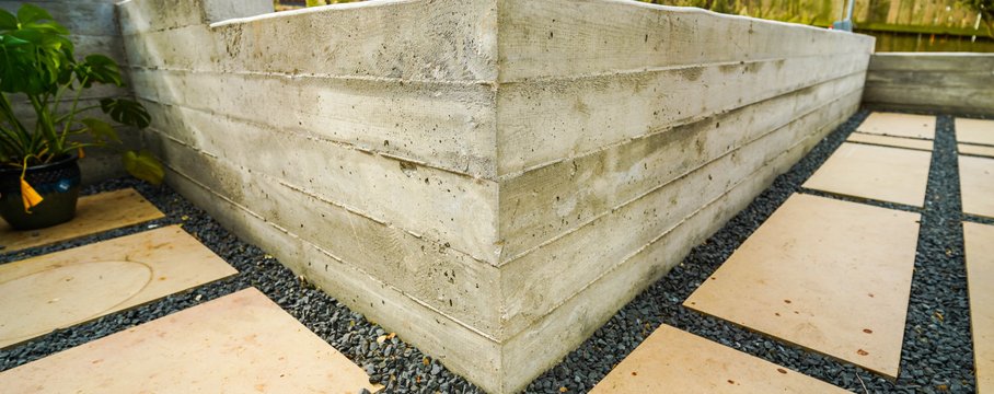 Gravel drainage course set behind a board-formed concrete retaining wall on a Shoal Creek property, the kind of gravel-and-outlet detail used in a French drain