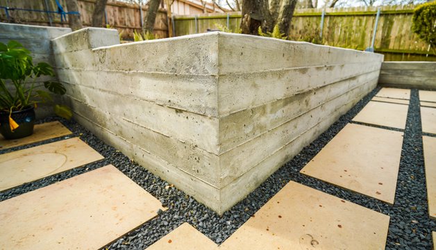 Board-formed concrete retaining wall beside a flagstone and gravel terrace in Austin