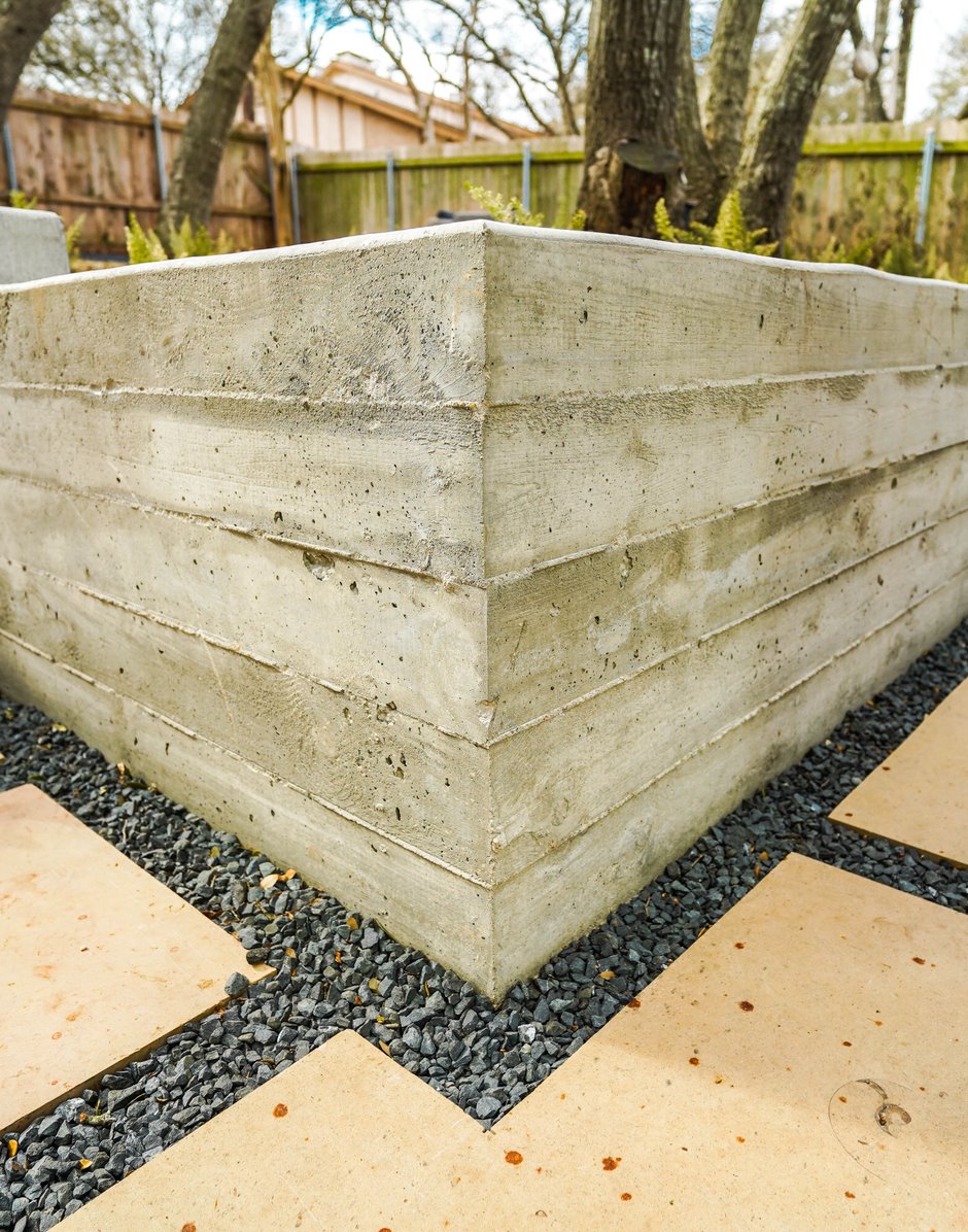 Board-formed concrete retaining wall meeting flagstone and gravel