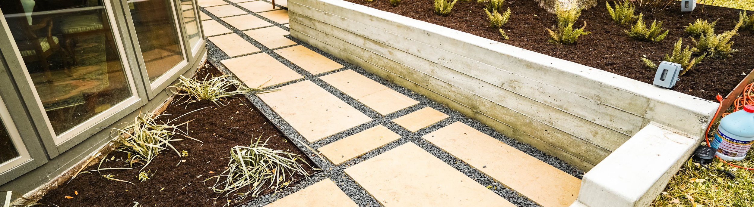 Terraced Austin backyard near Shoal Creek with a concrete retaining wall, gravel, a flagstone pathway, and planting beds that manage grade and drainage