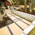 Terraced Austin backyard near Shoal Creek with a concrete retaining wall, gravel, a flagstone pathway, and planting beds that manage grade and drainage