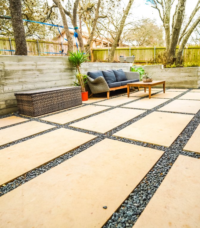 Board-formed concrete retaining wall holding a terraced flagstone patio in Austin