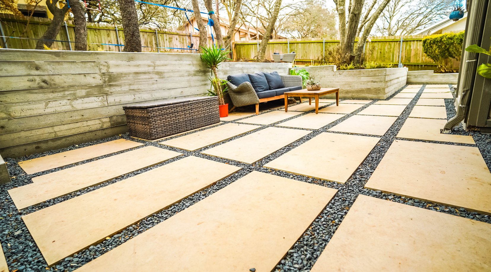 Cream paver patio framed by concrete walls and gravel joints