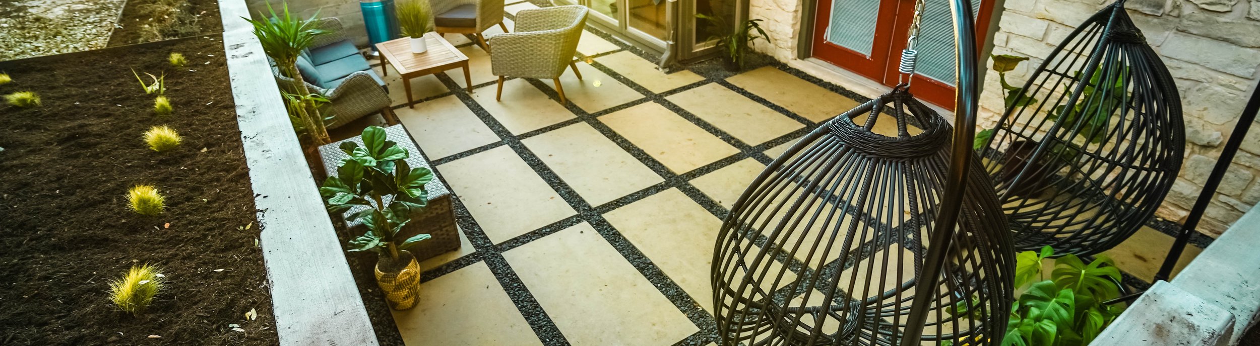Terraced Shoal Creek, Austin TX backyard with board-formed concrete walls and cream paver patios by Thrive Landscape and Design