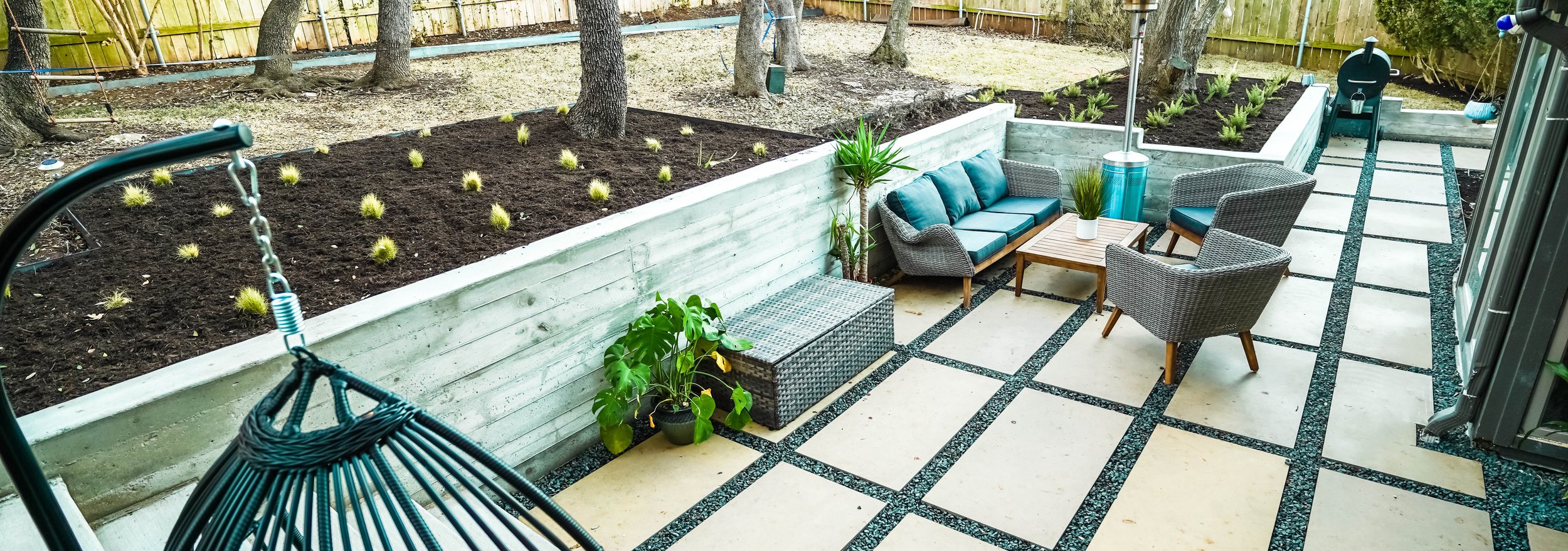 Wide view of the terraced patio, concrete walls, and newly planted raised beds