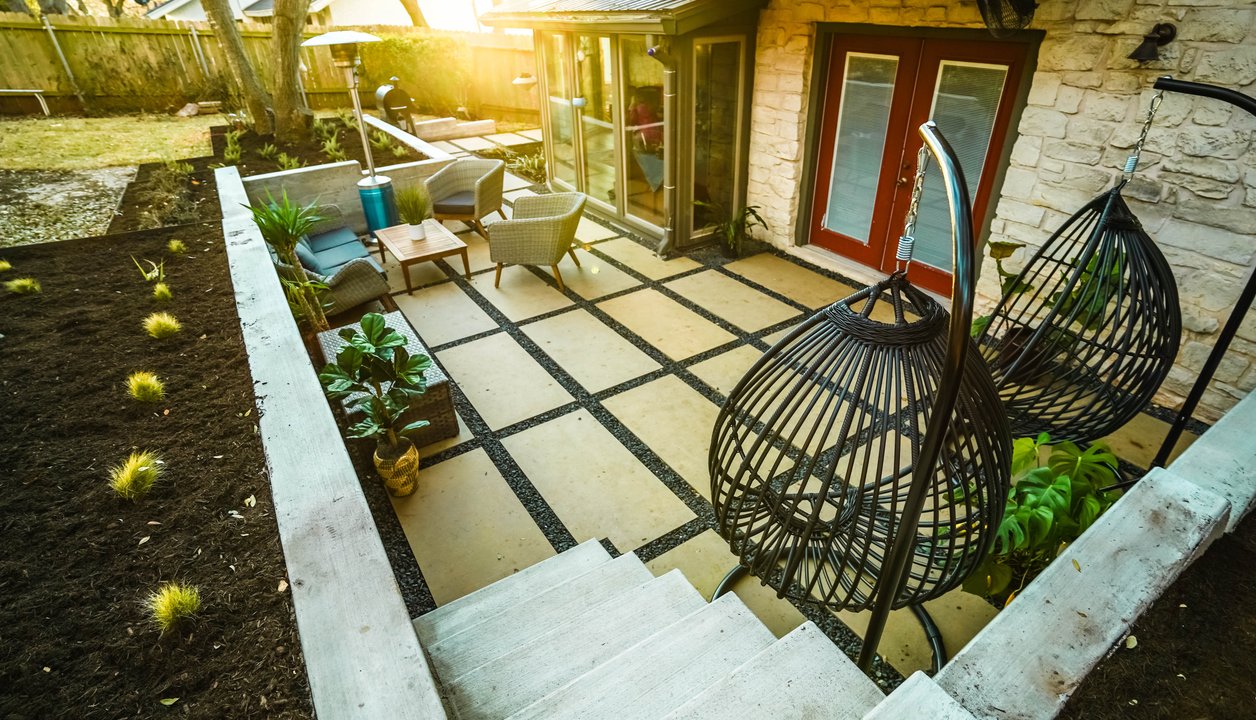 Terraced flagstone patio with gravel joints beside a concrete retaining wall in Austin