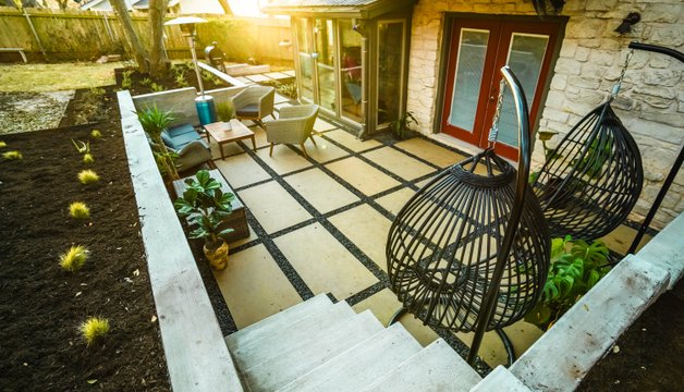 Shoal Creek backyard renovated with board-formed concrete retaining walls, flagstone patios, gravel, and new planting beds