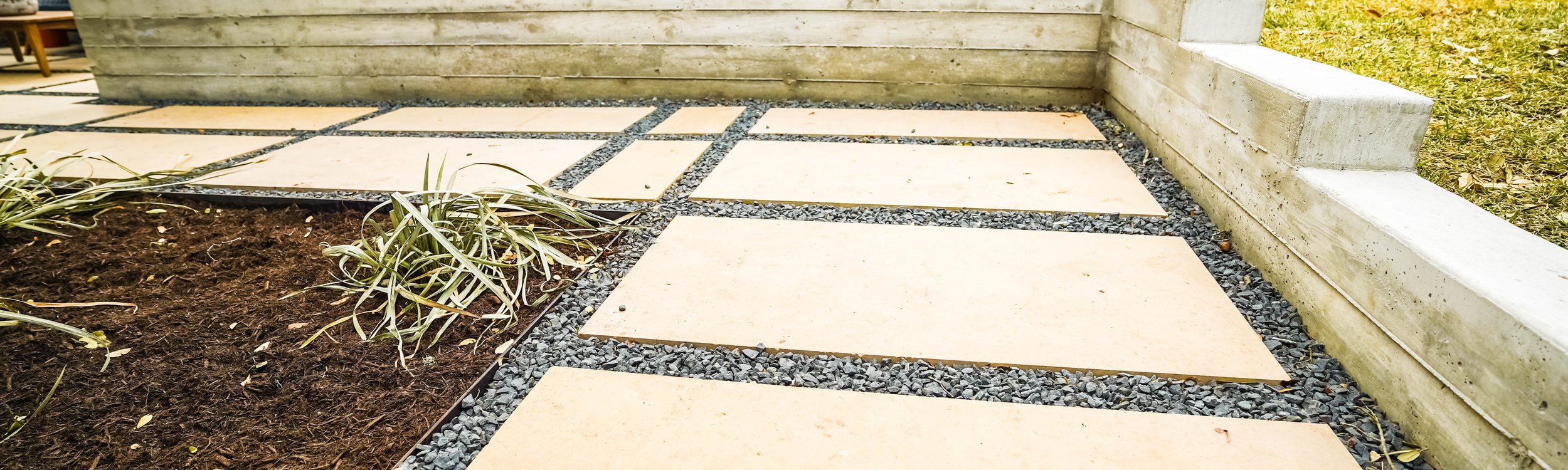 Terraced Austin backyard built with board-formed concrete retaining walls, flagstone patios, gravel, and steps