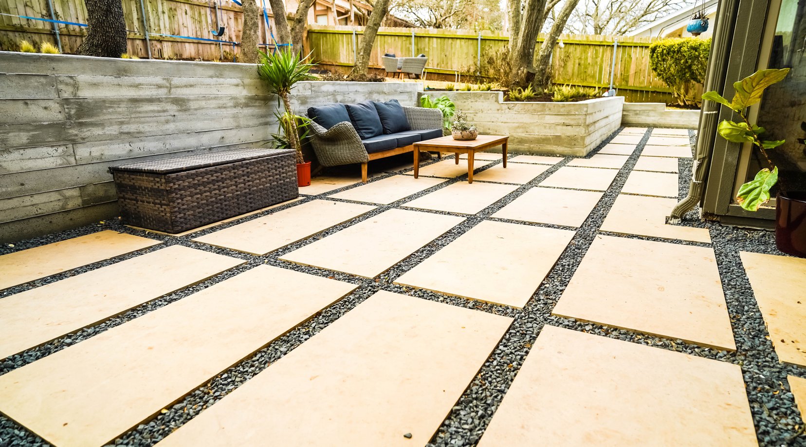 Large format cream pavers with gravel joints against the concrete wall